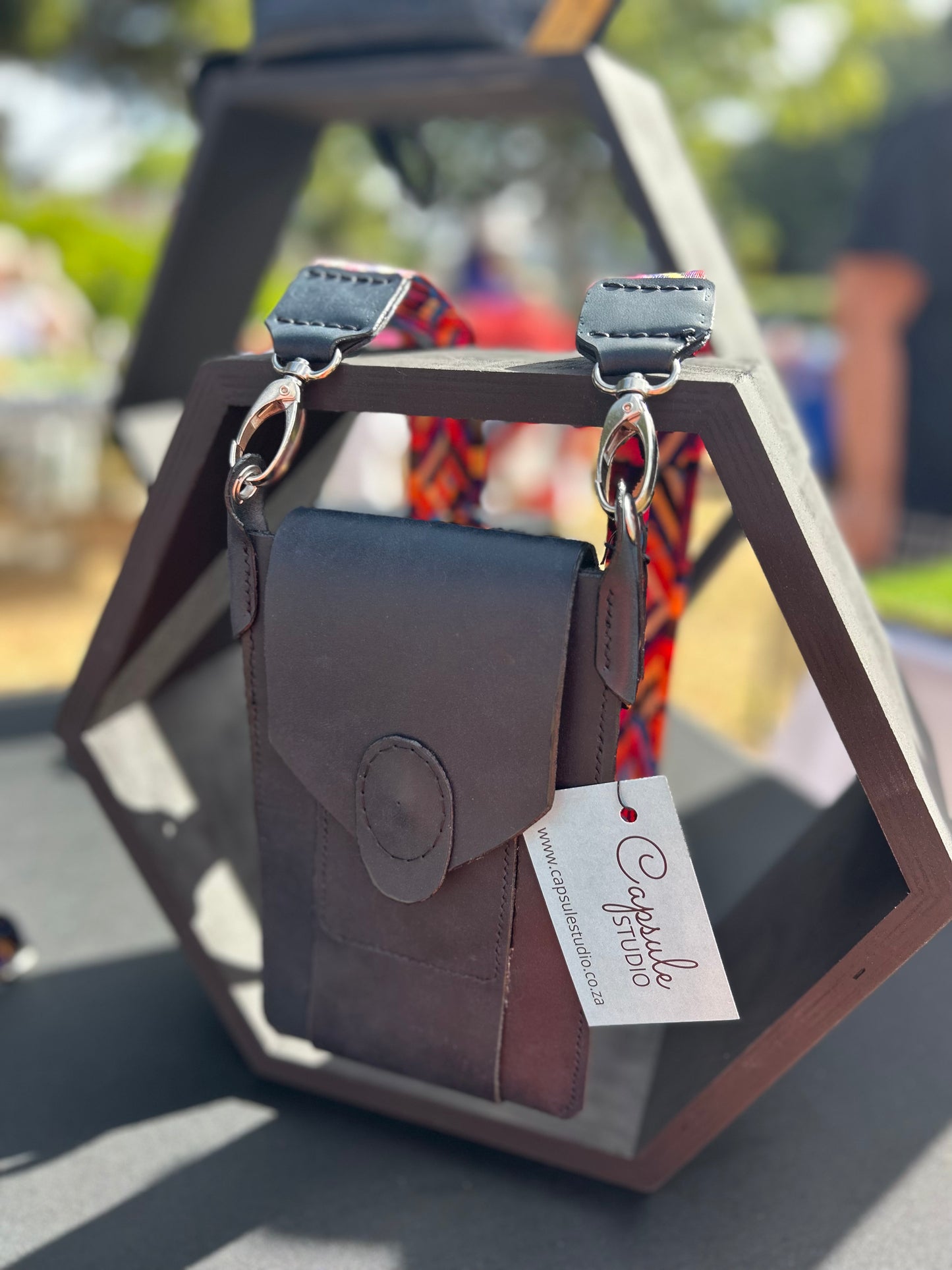 Leather phone bag in black with bright coloured woven strap.