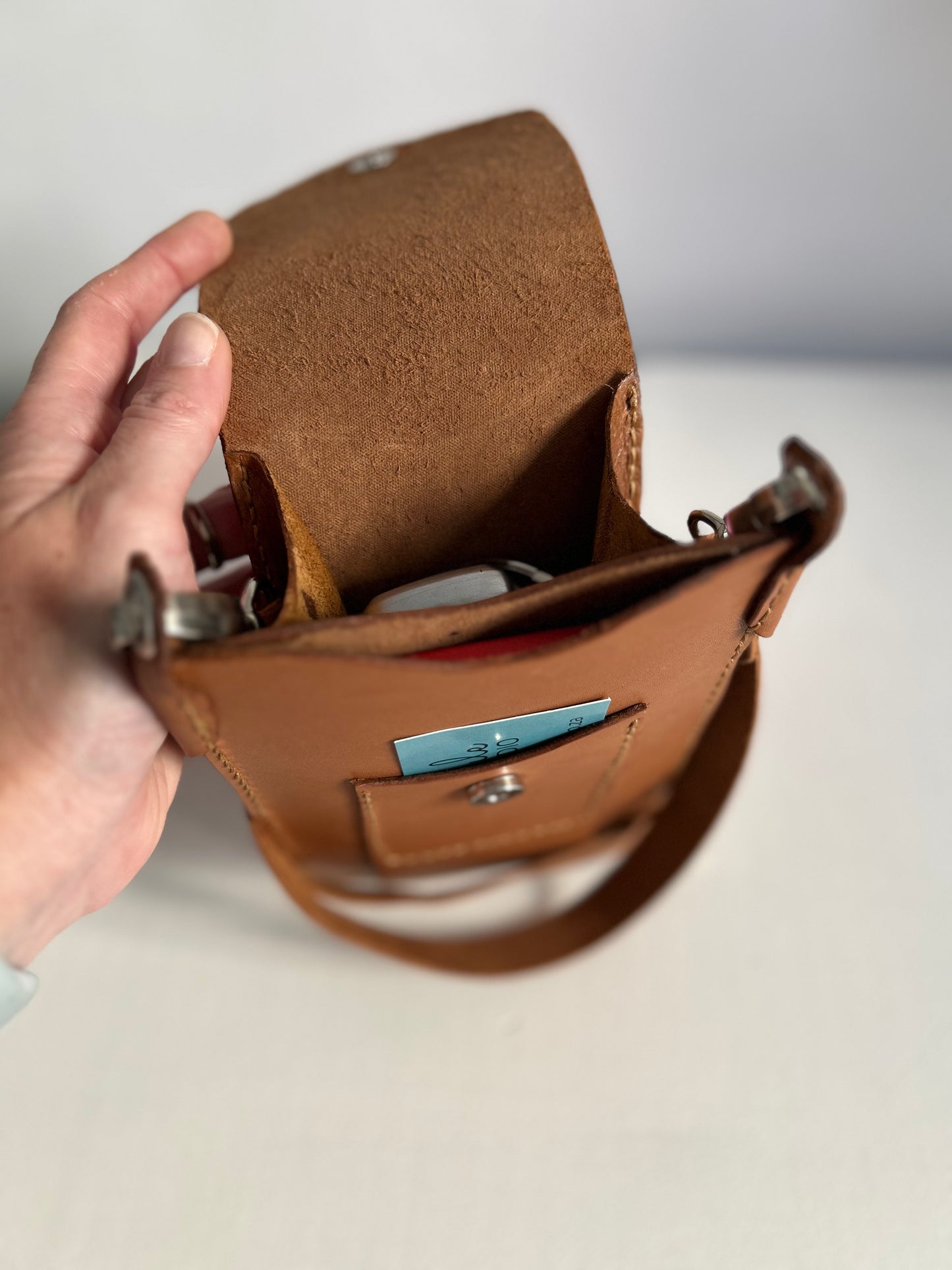 Light tan leather handbag suitable for holding a phone, one card and few smaller items. Bag open to show interior