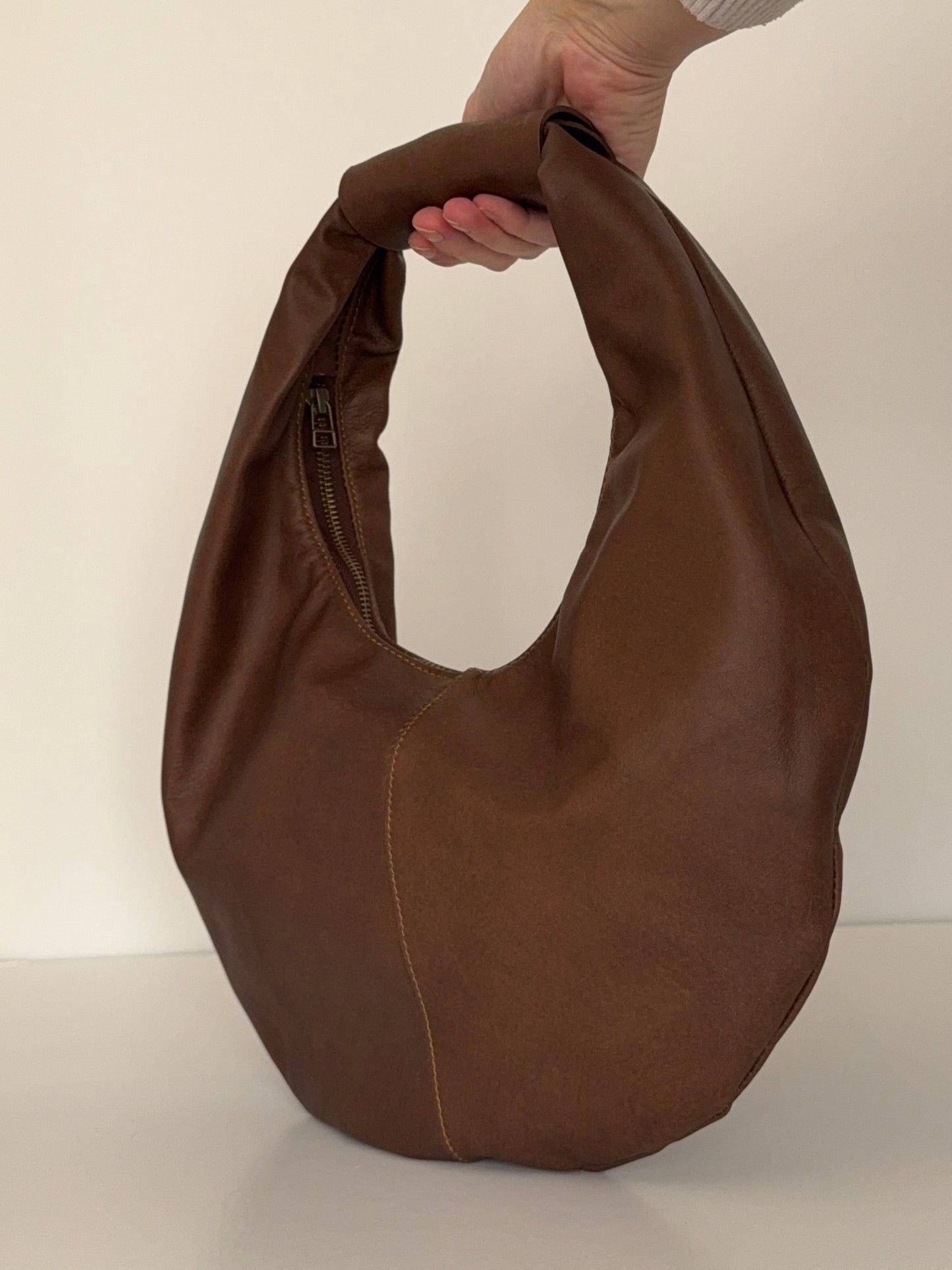 Brown bag held by a person against a white background