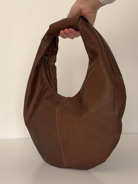 Brown bag held by a person against a white background
