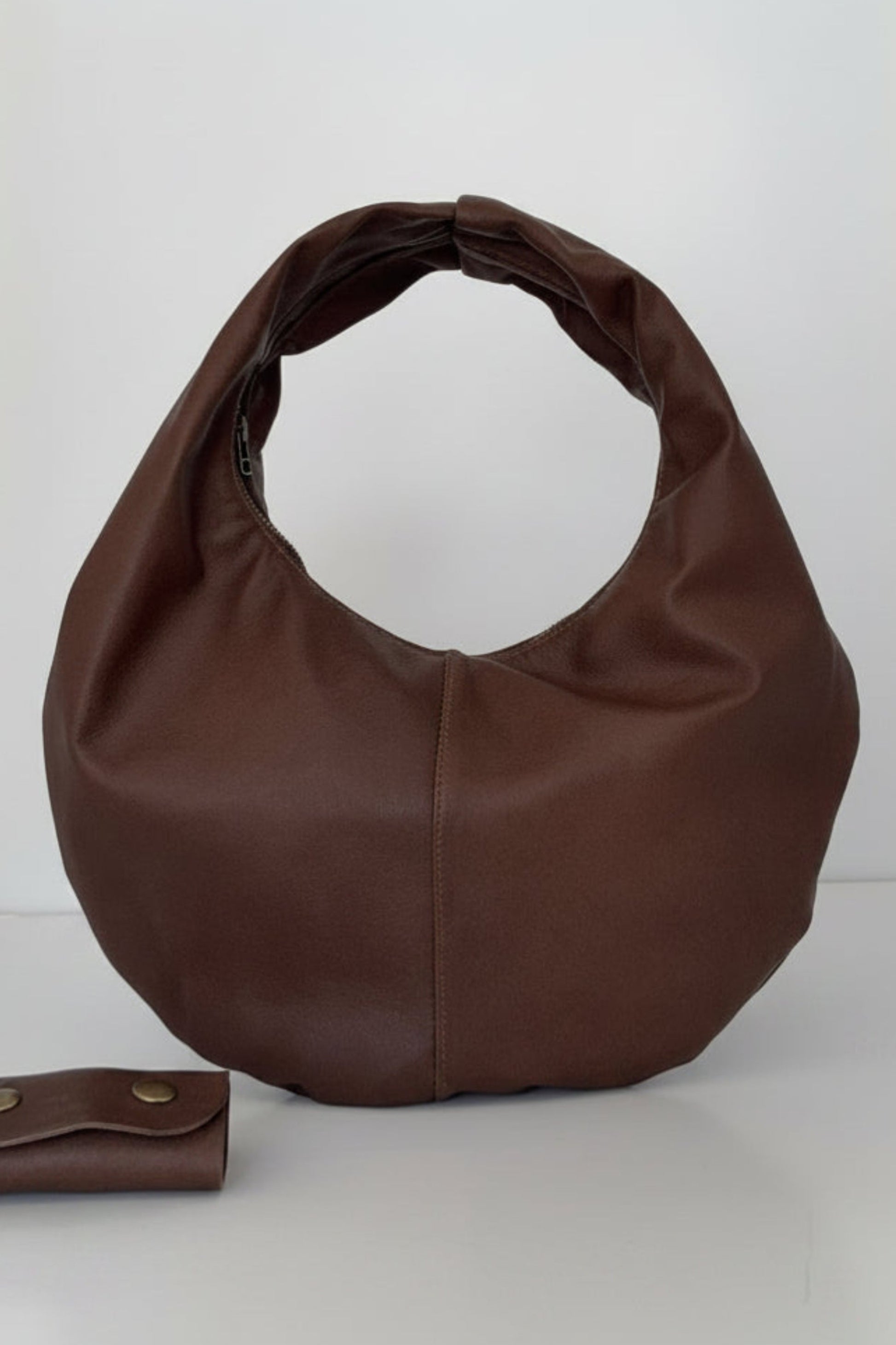 Brown leather bag hanging on a white wall